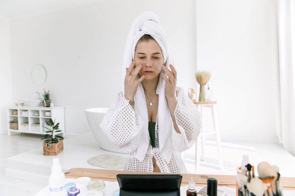 Woman in bathrobe applying skincare in a bright, serene bathroom. Perfect for beauty and wellness themes.