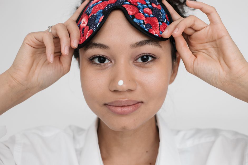 Close-up of a woman applying an eye mask, emphasizing beauty and self-care.