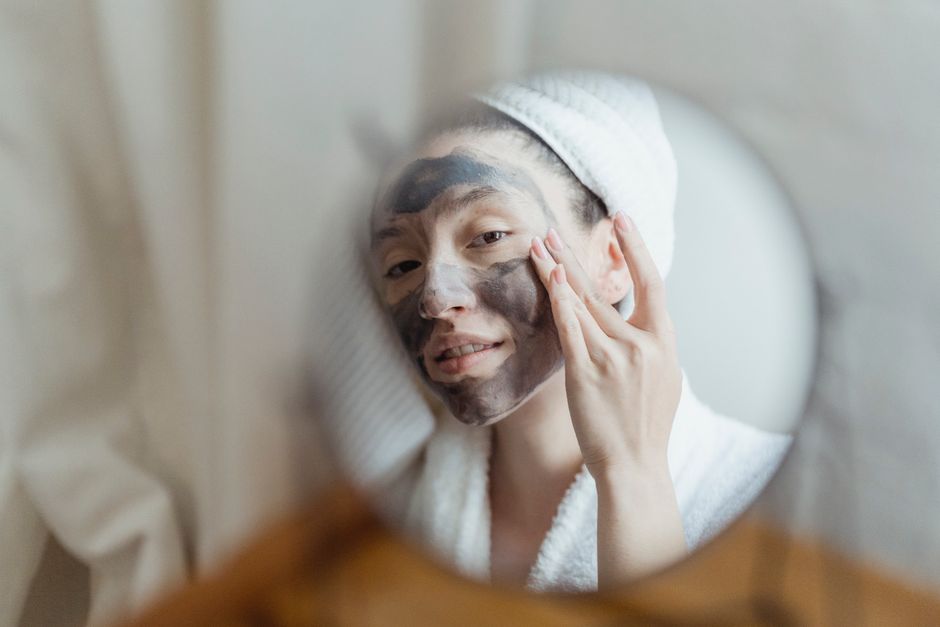 A woman enjoying a beauty routine with a face mask in an indoor setting.