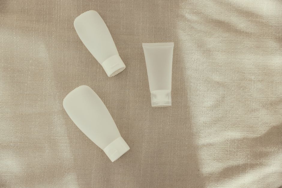 Flat lay image of minimalist plastic squeeze bottles on a textured surface.