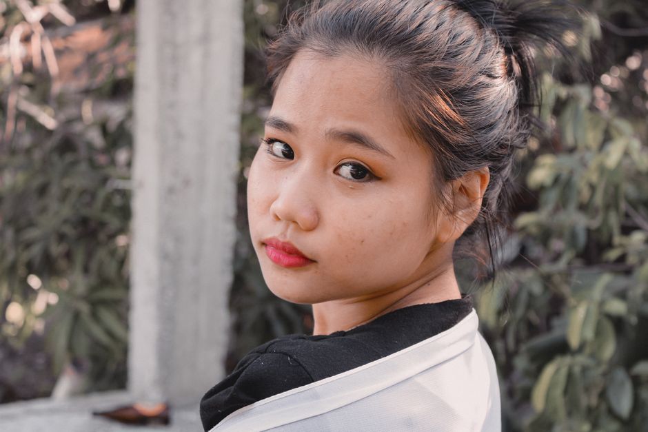 A thoughtful young woman with a serene expression outdoors.