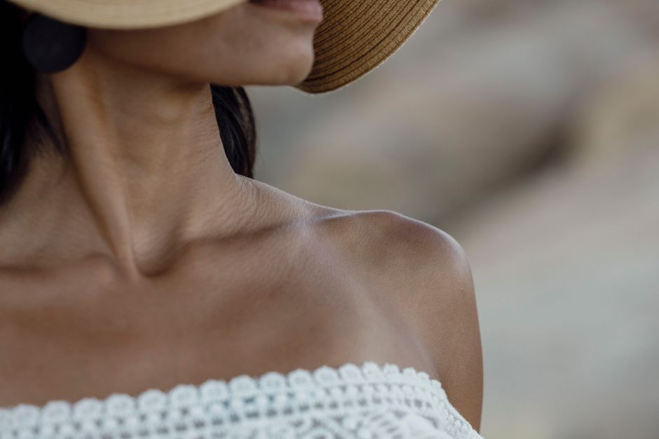 Close-up of a woman in a strapless top and hat, showcasing summer fashion with lace details.