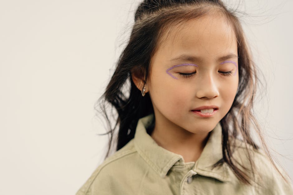 Close-up portrait of a young girl with purple face paint and eyes closed, exuding calmness.