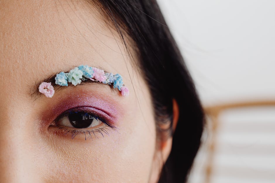 Close-up of an artistic floral eyebrow design with vibrant makeup for a creative look.