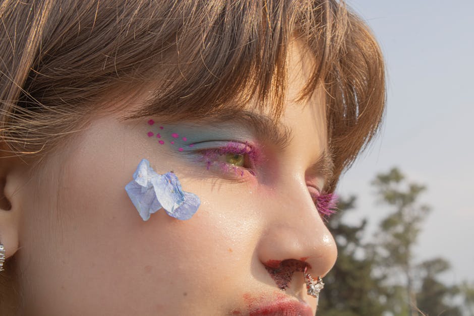 Close-up portrait featuring vibrant makeup and flower petals, creating an artistic and colorful look.