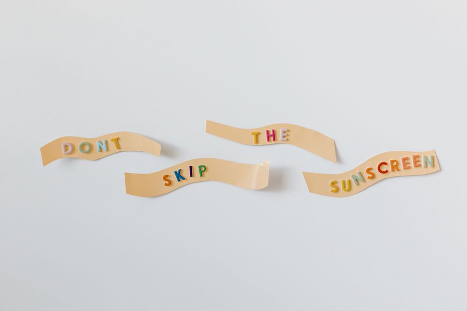 Colorful reminder to apply sunscreen with text on bandages on a white background.