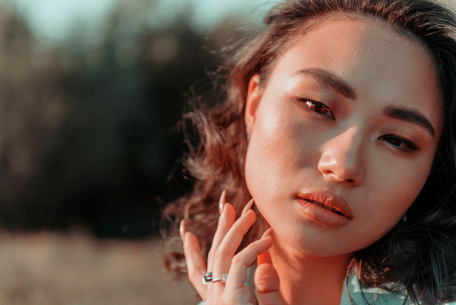Close-up portrait of a beautiful woman with makeup outdoors, showcasing elegance and serenity.