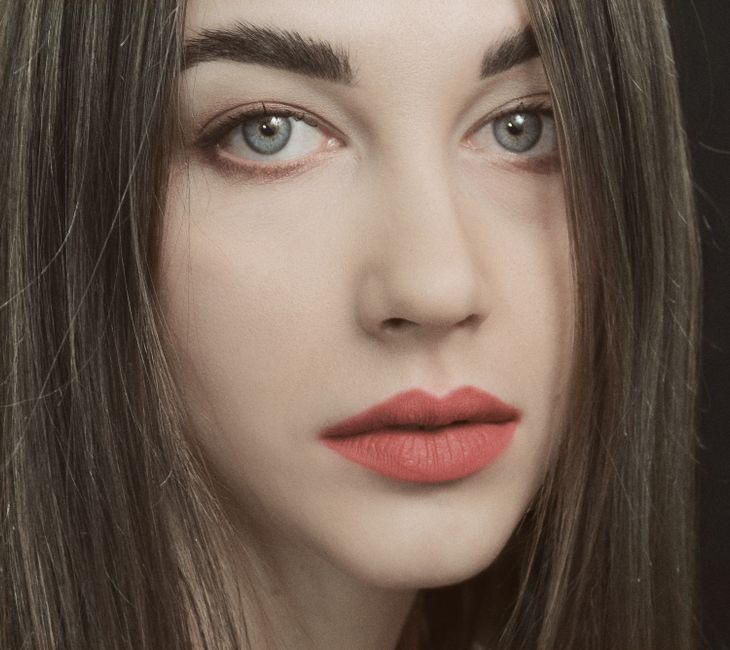 Stunning close-up portrait of a young woman with red lipstick and striking eyes.
