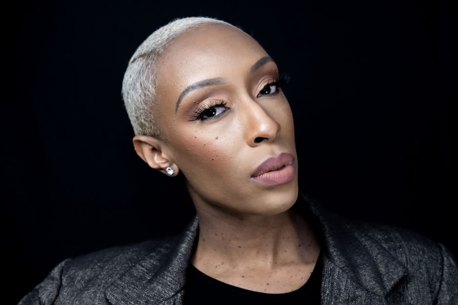 Stunning headshot of a woman with elegant makeup and short hair against a black background.