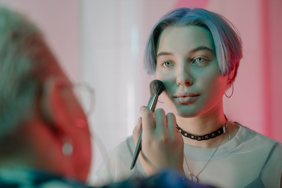 A woman with short dyed hair applying makeup in an artistic setting.