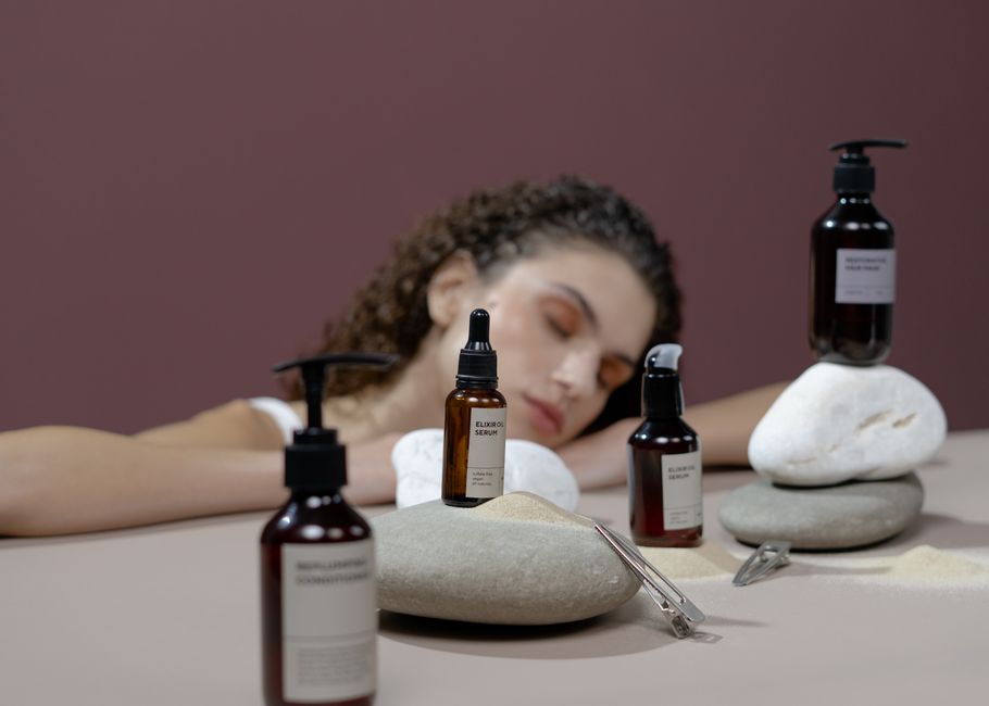 Woman with curly hair surrounded by natural stones and haircare products, eyes closed.