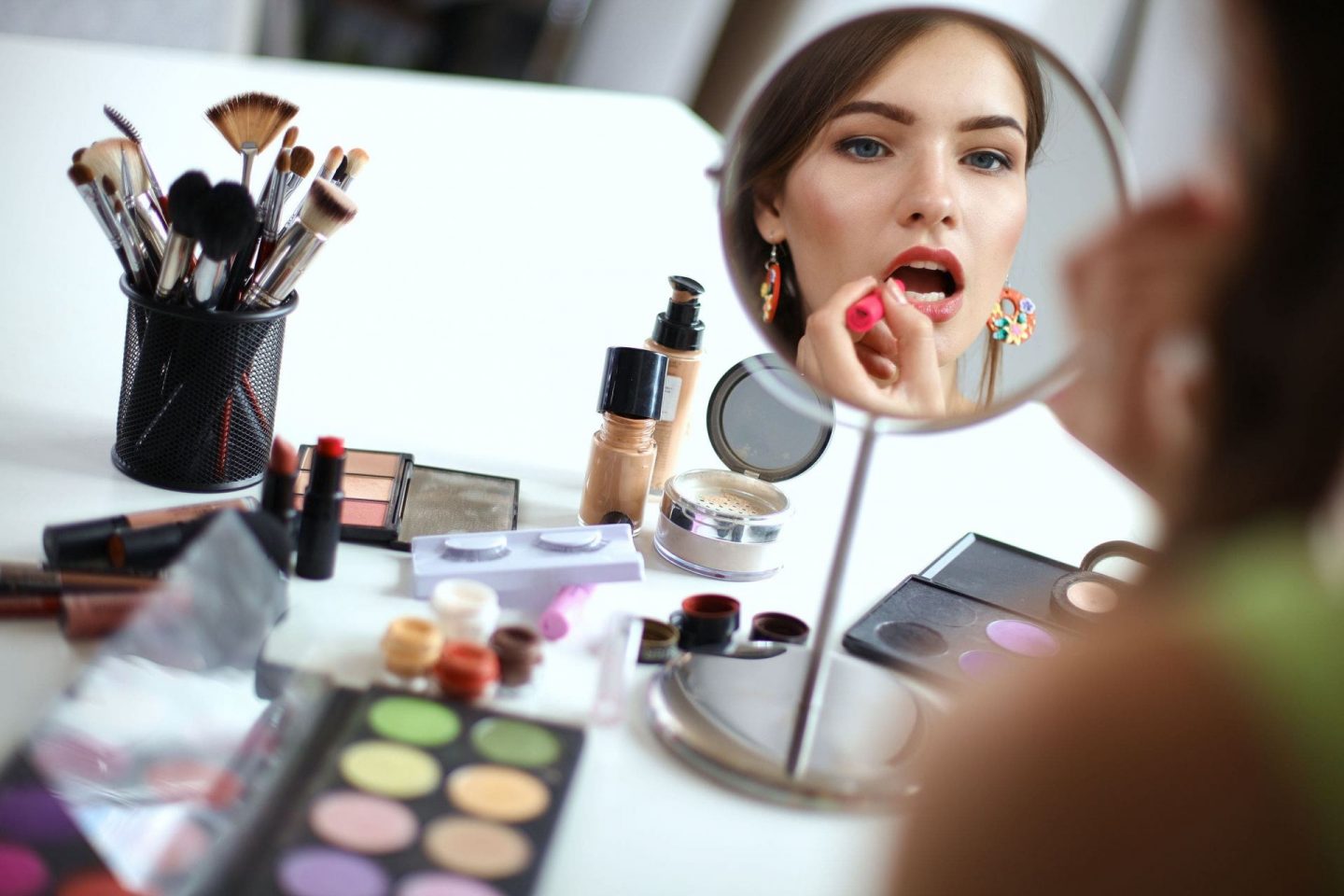 Woman applying makeup in a vanity mirror