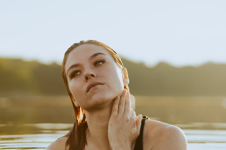 A serene portrait of a woman in water, exuding calmness and introspection at sunset.