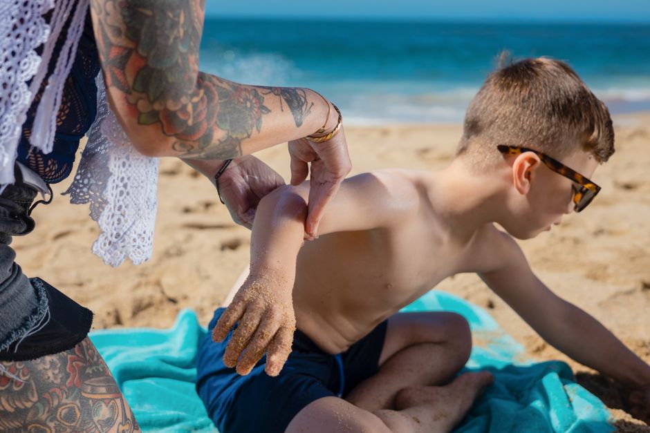 A child applies sunscreen on a sunny beach day, ensuring skin protection.