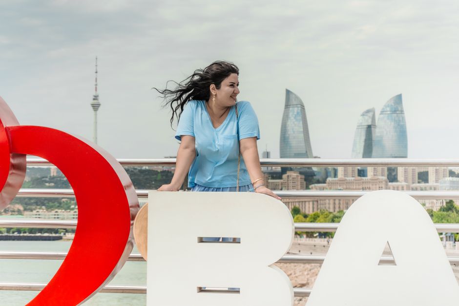 A woman in Baku overlooks the city skyline featuring the iconic Flame Towers.