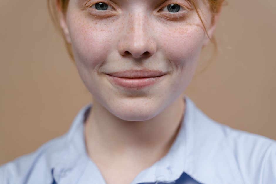 A smiling redhead girl with freckles captured in a warm, close-up portrait.