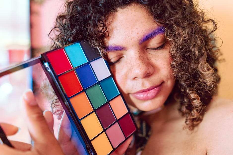 Vibrant portrait of a woman embracing a colorful makeup palette and bold purple eyebrows.